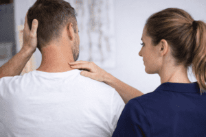 Neck sprain physiotherapy assessment of male patient from behind