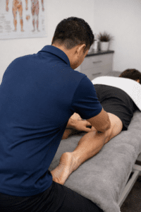 Remedial vs relaxation massage therapist applying focused hamstring treatment during clinic session