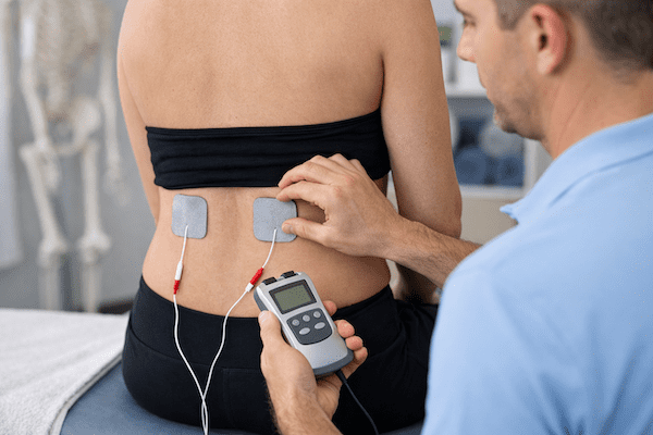 TENS machine electrodes placed on lower back for pain relief treatment