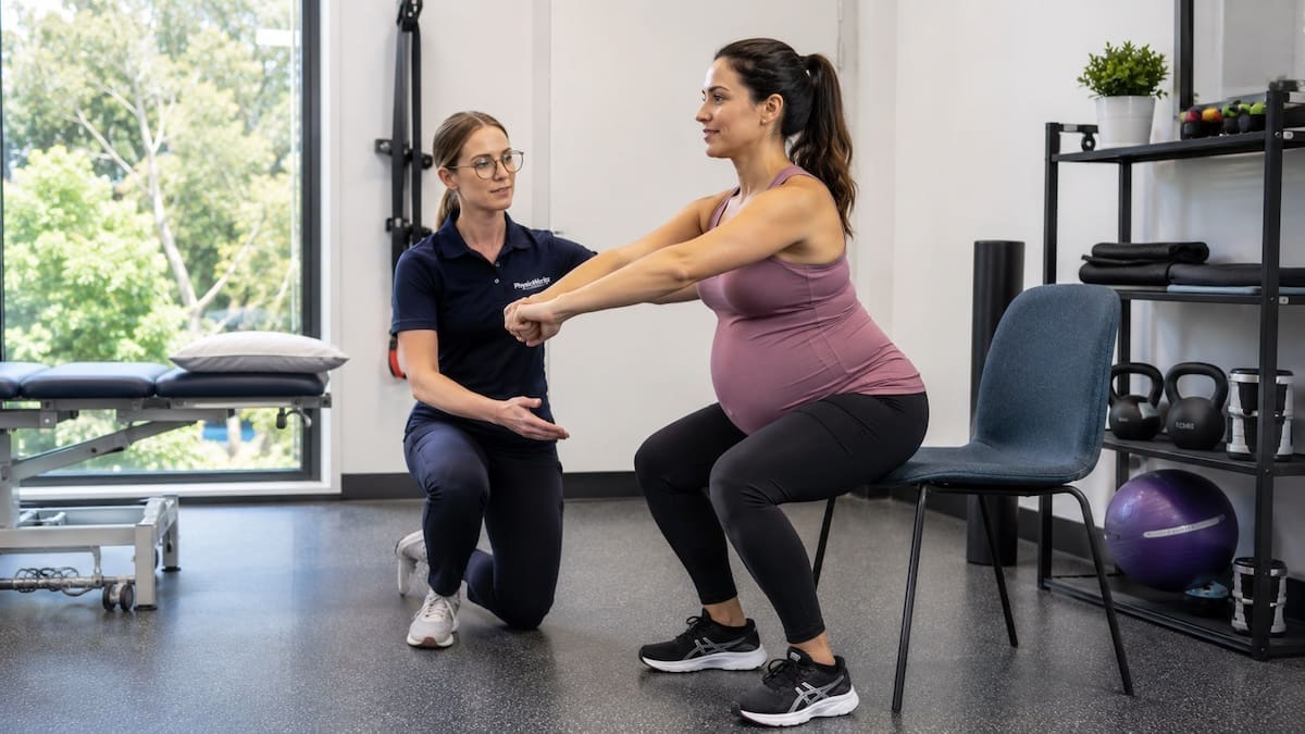 Safe pregnancy exercises with physiotherapist guiding supported chair squat