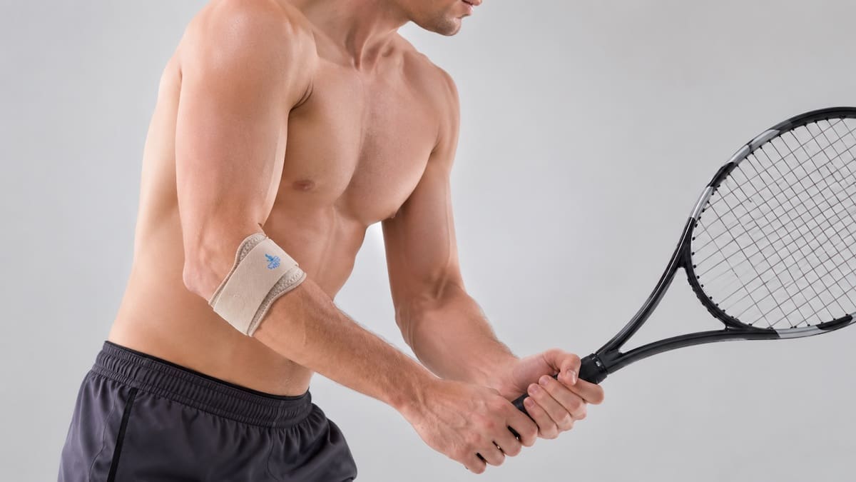 tennis-elbow-brace-racquet-grip Tennis elbow brace positioned on the upper forearm while holding a tennis racquet